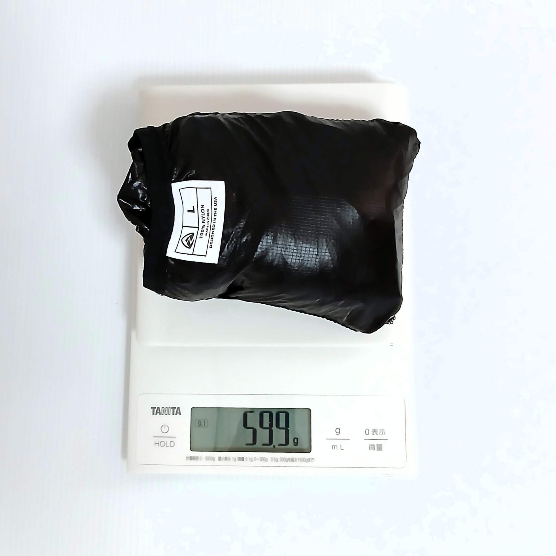 Zpacks Ventum Wind Shell Jacket ベンタムウインドシェルジャケット Black Lサイズを収納しデジタルスケールで計量、実測59.9gを表示。タグに100% NYLON・MADE IN THE USA表記の実物写真 - 山道具とULギアのお店 Ascend Lite