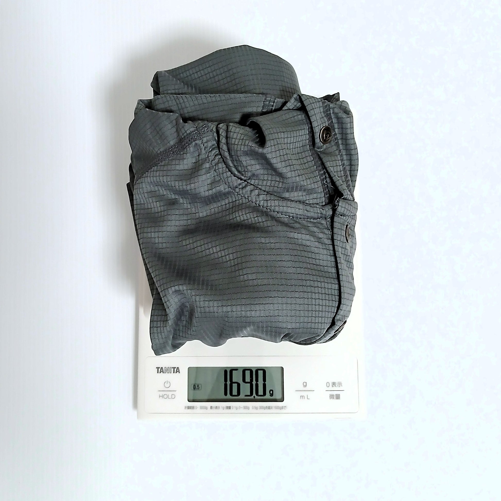 Zpacks Trail Cool Sun Hoody トレイルクールサンフーディ Gray Lサイズを畳んでデジタルスケールで計量、実測169.0gを表示。胸元のスナップボタンが視認できる実物写真 - 山道具とULギアのお店 Ascend Lite