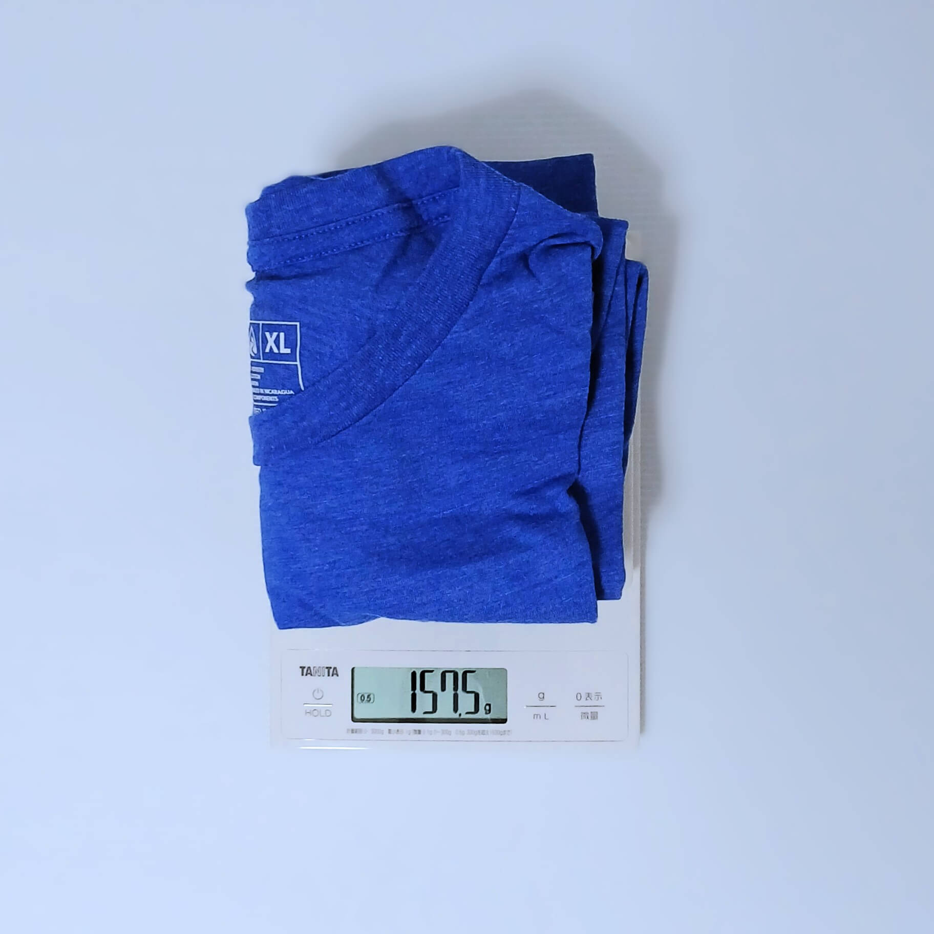 Zpacks Crest T-Shirt クレストTシャツ ブルーのXLサイズを畳んでデジタルスケールにのせ、157.5gを表示した計量の実物写真。首元にXLサイズのタグ - 山道具とULギアのお店 Ascend Lite