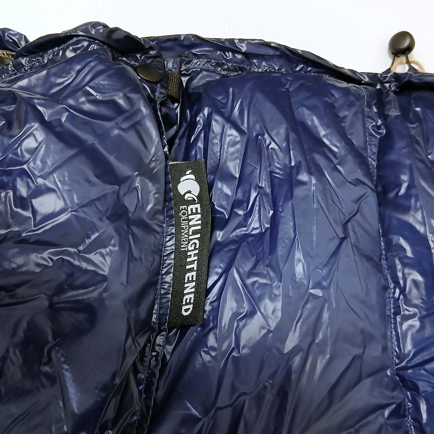 Enlightened Equipment Revelation Sleeping Quilt 50°F Navy 10D 首元の拡大・スナップとドローコード・コードロック、縫い付けられたブランドラベルの実物写真 - 山道具とULギアのお店 Ascend Lite