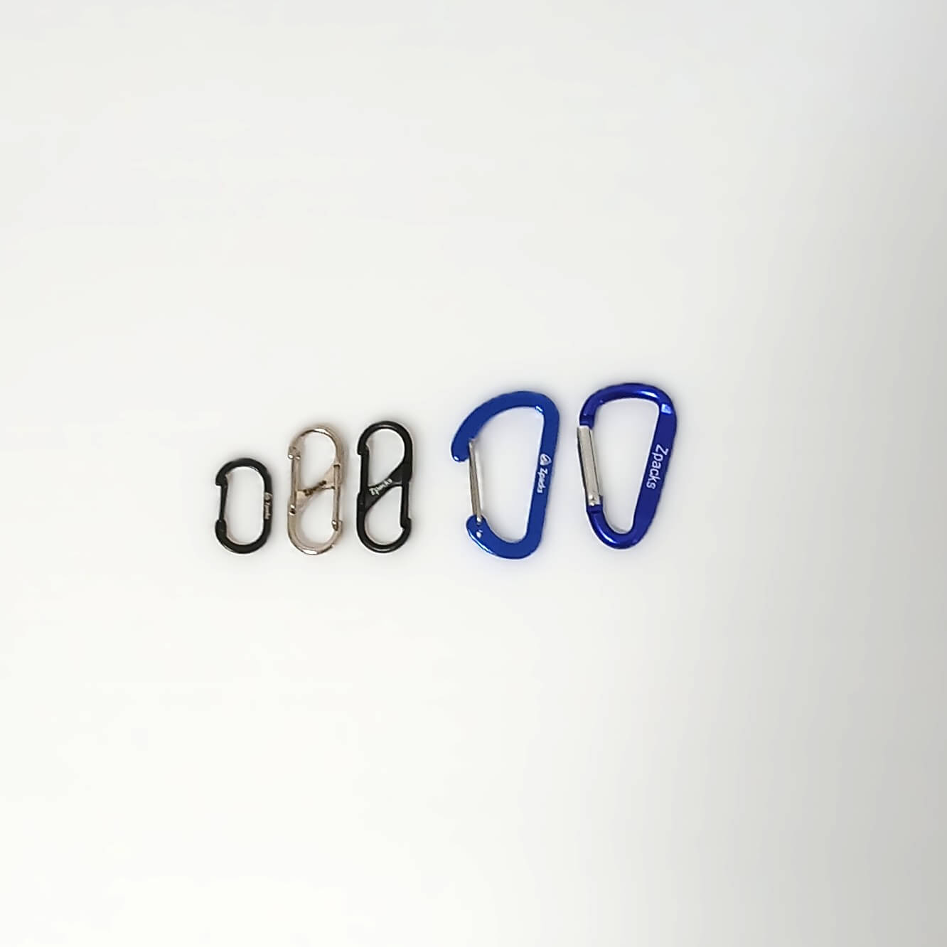 Zpacks Carabiner 4個セット カラビナ 全タイプのサイズ比較 左からブラックのTiny Oval、シルバーとブラックのMini-S、ブルーのMini-Dワイヤーゲートとスタンダードゲートを白背景に横並びにした実物写真 - 山道具とULギアのお店 Ascend Lite