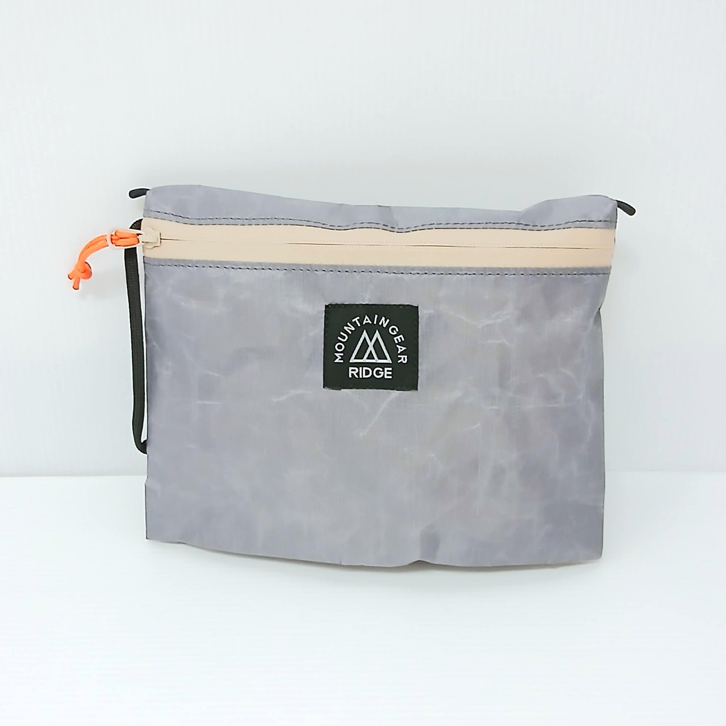 RIDGE MOUNTAIN GEAR Travel Pouch Plus トラベルポーチプラス 中身を入れて膨らませた正面（ロゴタグとオレンジのジッパープル） - 山道具とULギアのお店 Ascend Lite