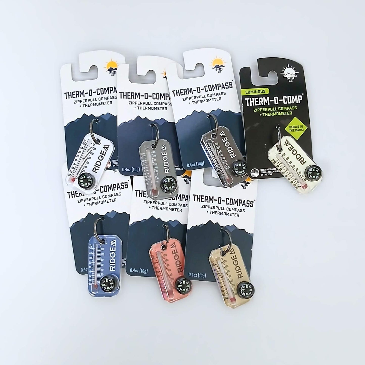 RIDGE MOUNTAIN GEAR Therm-o-compass サーモコンパス 全7色（White・Grey・Black・LumaGage・Palace Blue・Bubblegum・Soft Sand）をパッケージ台紙付きで並べた実物写真 - 山道具とULギアのお店 Ascend Lite