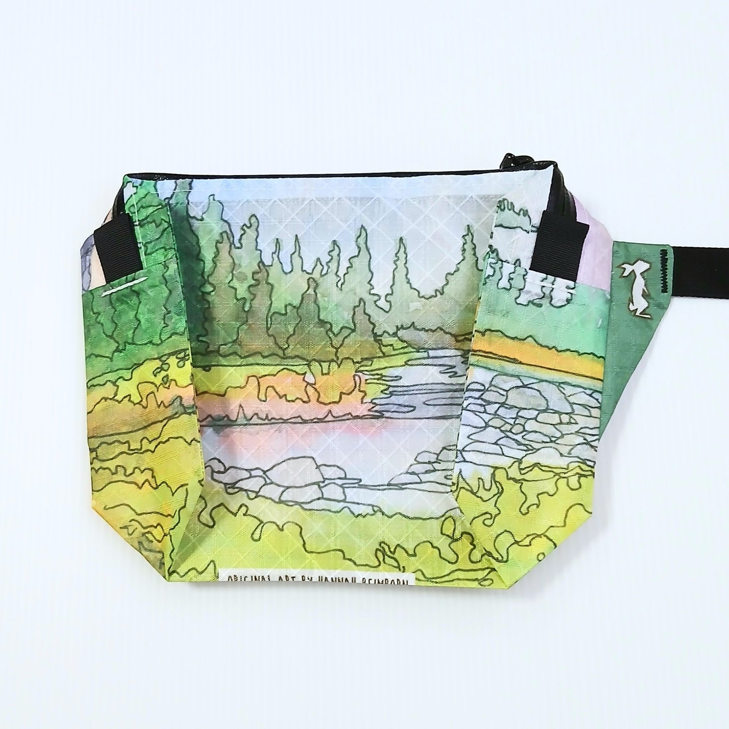 High Tail Designs The Ultralight Fanny Pack ファニーパック Boulder Canyon（Hannah Beimborn） 新緑の草地と針葉樹林、中央を流れる小川と灰色の岩を水彩線画で描いた柄の正面全体と、グリーンのストラップ基部・下端のアーティストクレジット印字の実物写真 - 山道具とULギアのお店 Ascend Lite