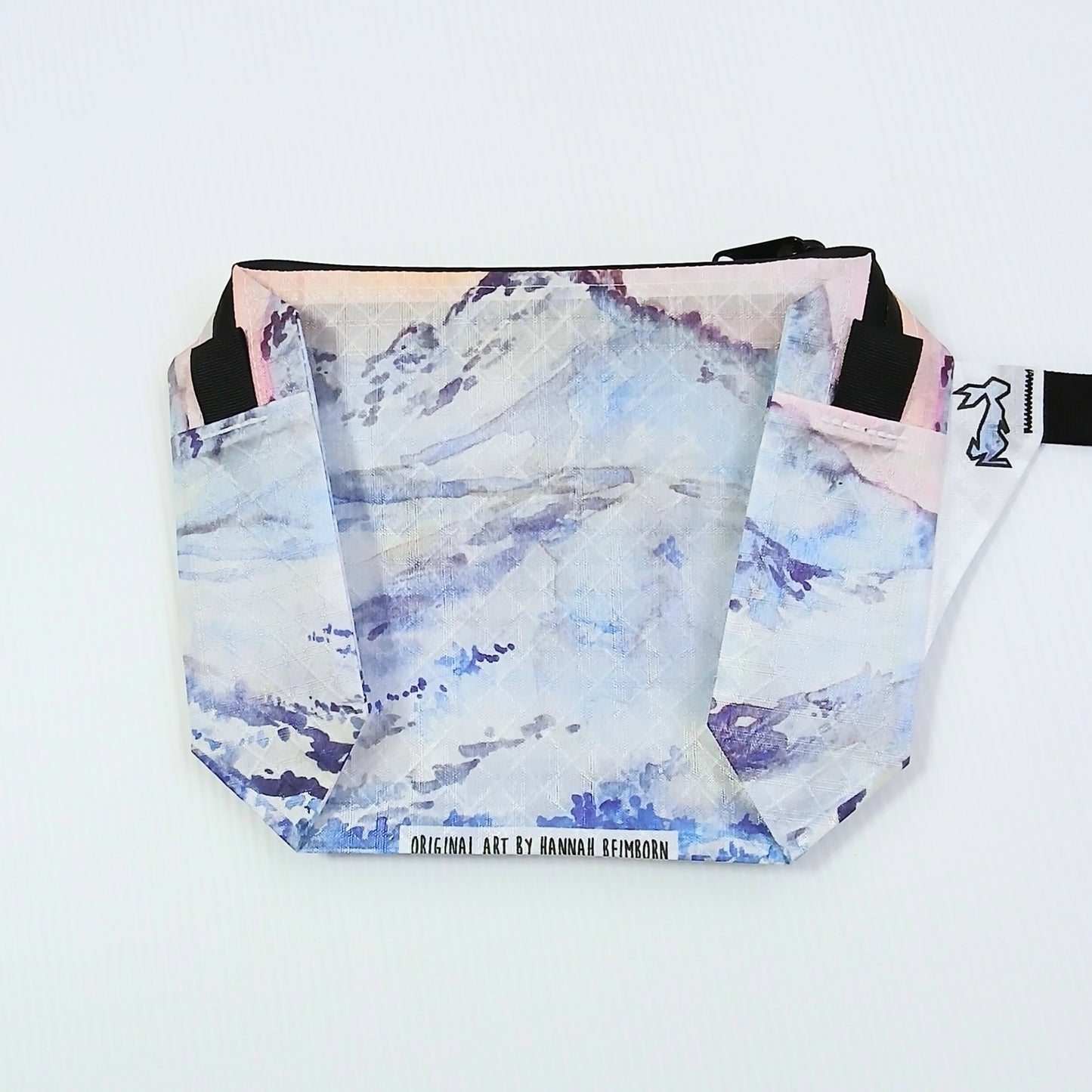 High Tail Designs The Ultralight Fanny Pack ファニーパック The Citadel（Hannah Beimborn） 白と淡青の雪の斜面の上にピンクの朝焼け空が広がる柄の正面全体と、下端の黒文字のアーティストクレジット印字の実物写真 - 山道具とULギアのお店 Ascend Lite