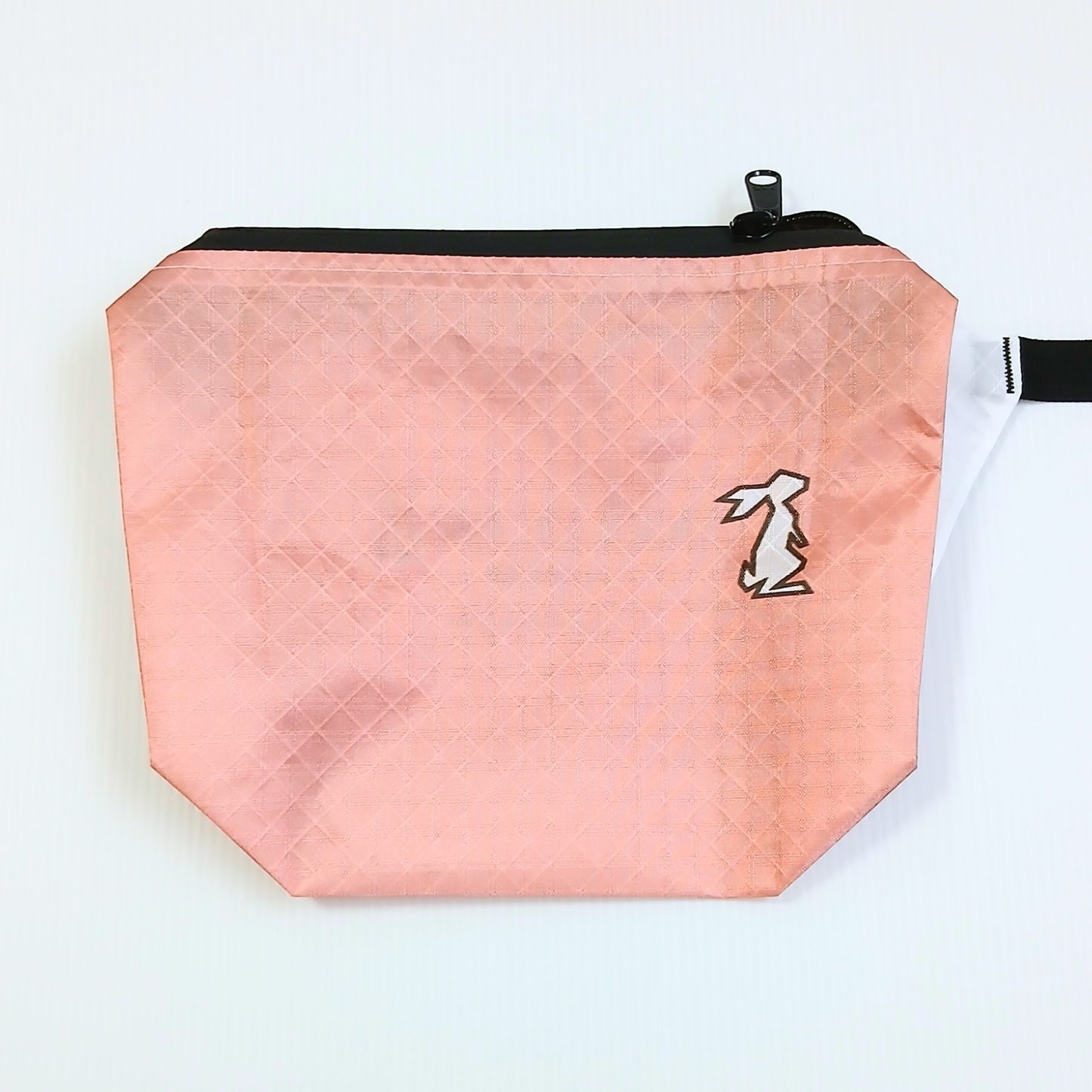 High Tail Designs The Ultralight Fanny Pack v1.5 ファニーパック v1.5 Coral 淡いサーモンピンクの無地生地に白いウサギのロゴ、底に向かって膨らむマチと白いストラップキーパーが見える前面の実物写真 - 山道具とULギアのお店 Ascend Lite