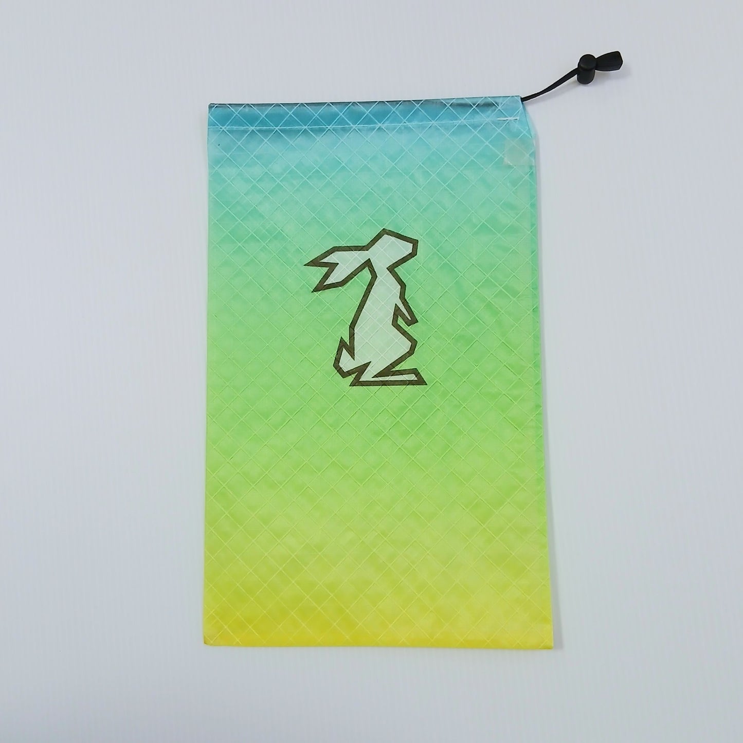 High Tail Designs Ultralight Drawstring Stuff Sack ドローストリングスタッフサック Citron ターコイズから黄緑・レモンイエローへ縦に流れるグラデーション柄、中央に地の色が透けるウサギの輪郭ロゴの実物写真 - 山道具とULギアのお店 Ascend Lite