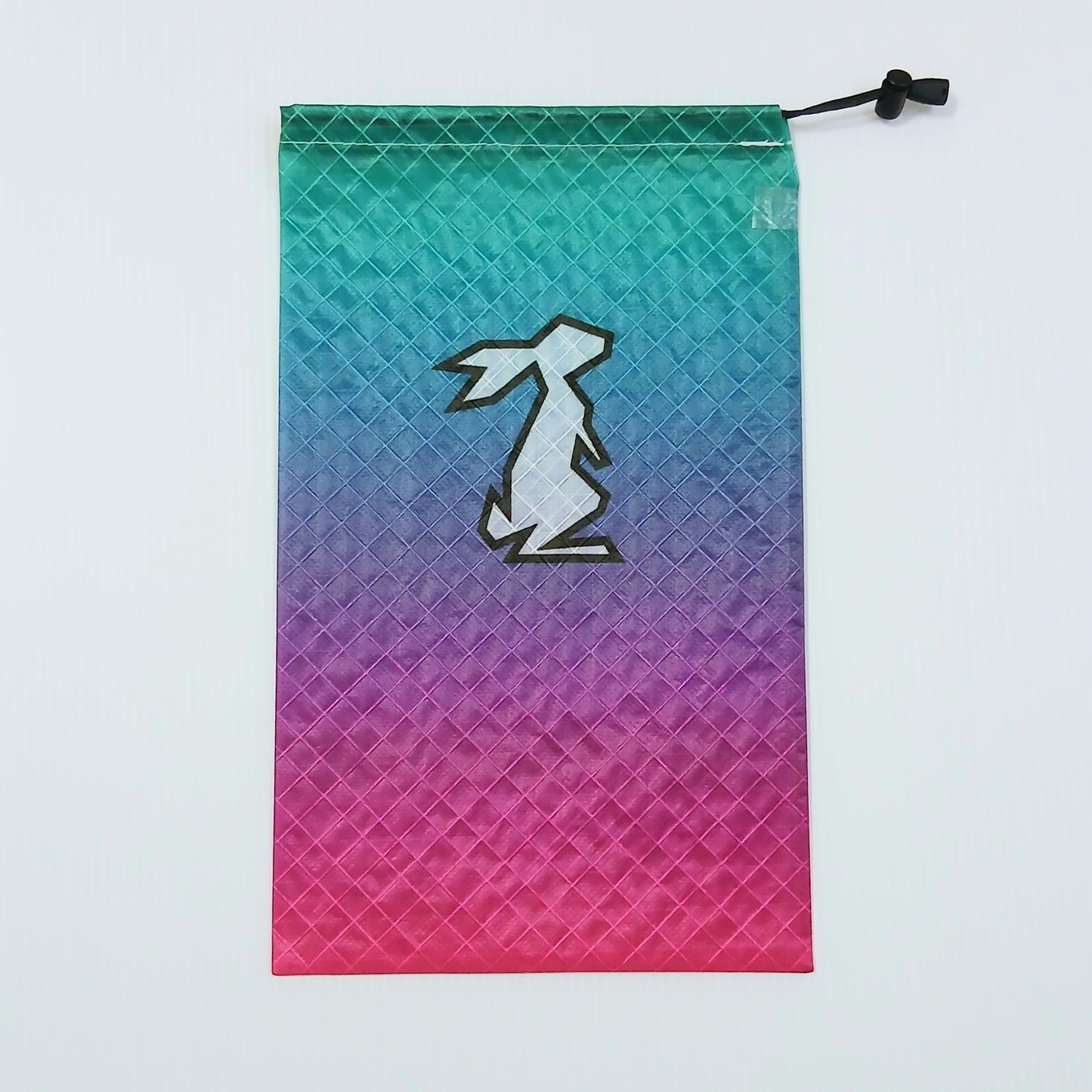 High Tail Designs Ultralight Drawstring Stuff Sack ドローストリングスタッフサック Stellar ティールグリーンから青紫・マゼンタピンクへ斜めに流れるグラデーション柄、中央に白いウサギ輪郭ロゴ、右上に黒いコードロックの実物写真 - 山道具とULギアのお店 Ascend Lite
