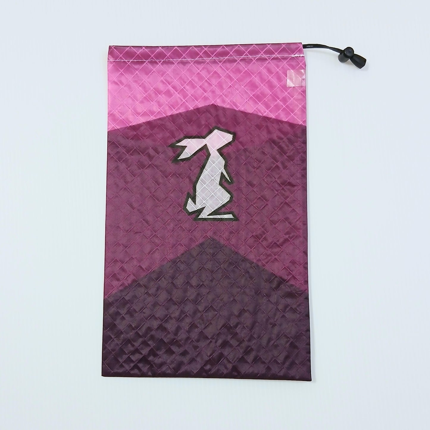 High Tail Designs Ultralight Drawstring Stuff Sack ドローストリングスタッフサック Dreaming ピンクの空にワインレッドと濃紫の山を二段に重ねたカラーブロック柄、中央に淡ピンクのウサギのシルエットの実物写真 - 山道具とULギアのお店 Ascend Lite