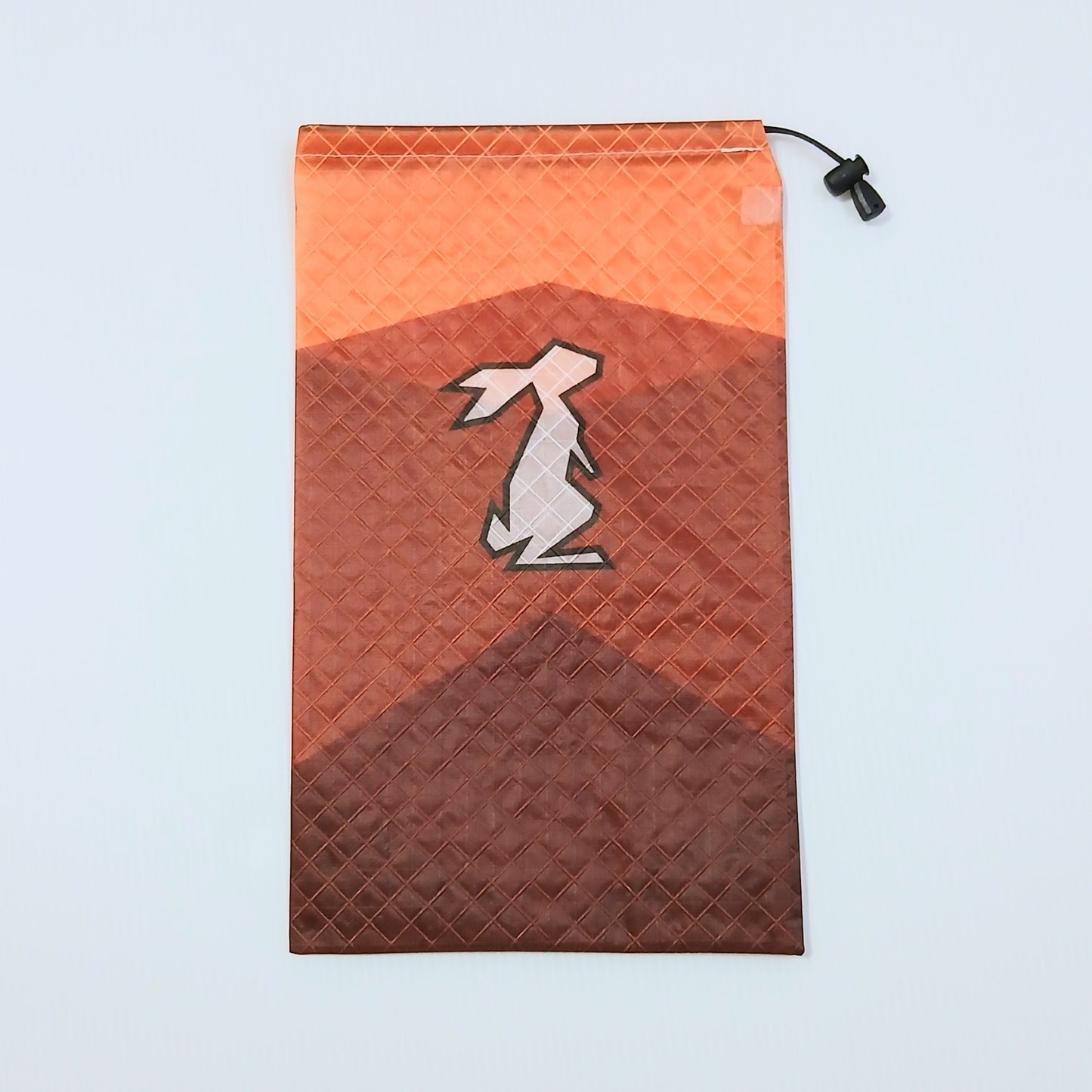 High Tail Designs Ultralight Drawstring Stuff Sack ドローストリングスタッフサック Long Trail オレンジの空に赤茶とこげ茶の山を二段に重ねたカラーブロック柄、中央に淡ピンクのウサギのシルエットの実物写真 - 山道具とULギアのお店 Ascend Lite