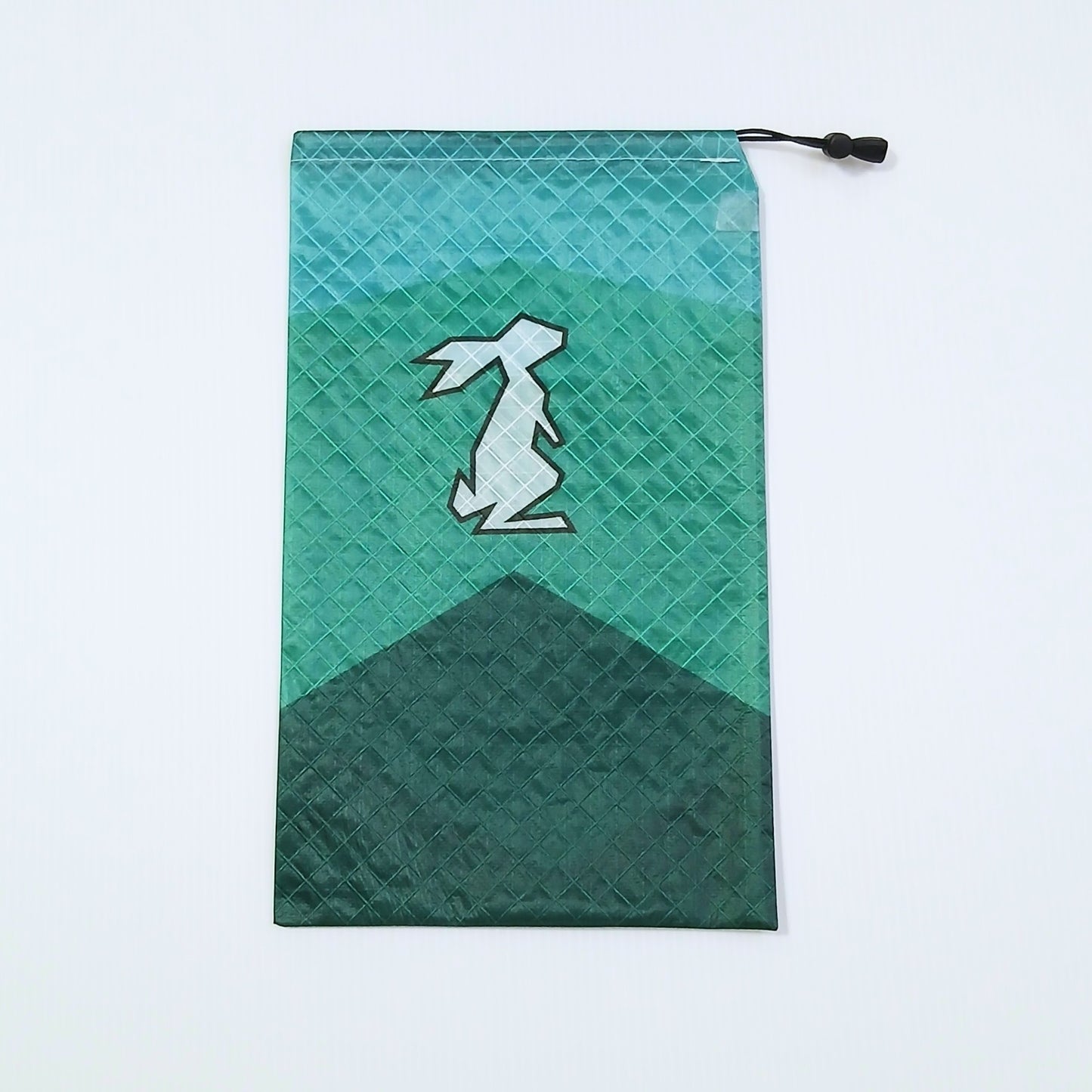High Tail Designs Ultralight Drawstring Stuff Sack ドローストリングスタッフサック Aquafight 明るいティールの空から深緑の三角の山へ切り替わる山型カラーブロック柄、中央に白いウサギのシルエットの実物写真 - 山道具とULギアのお店 Ascend Lite