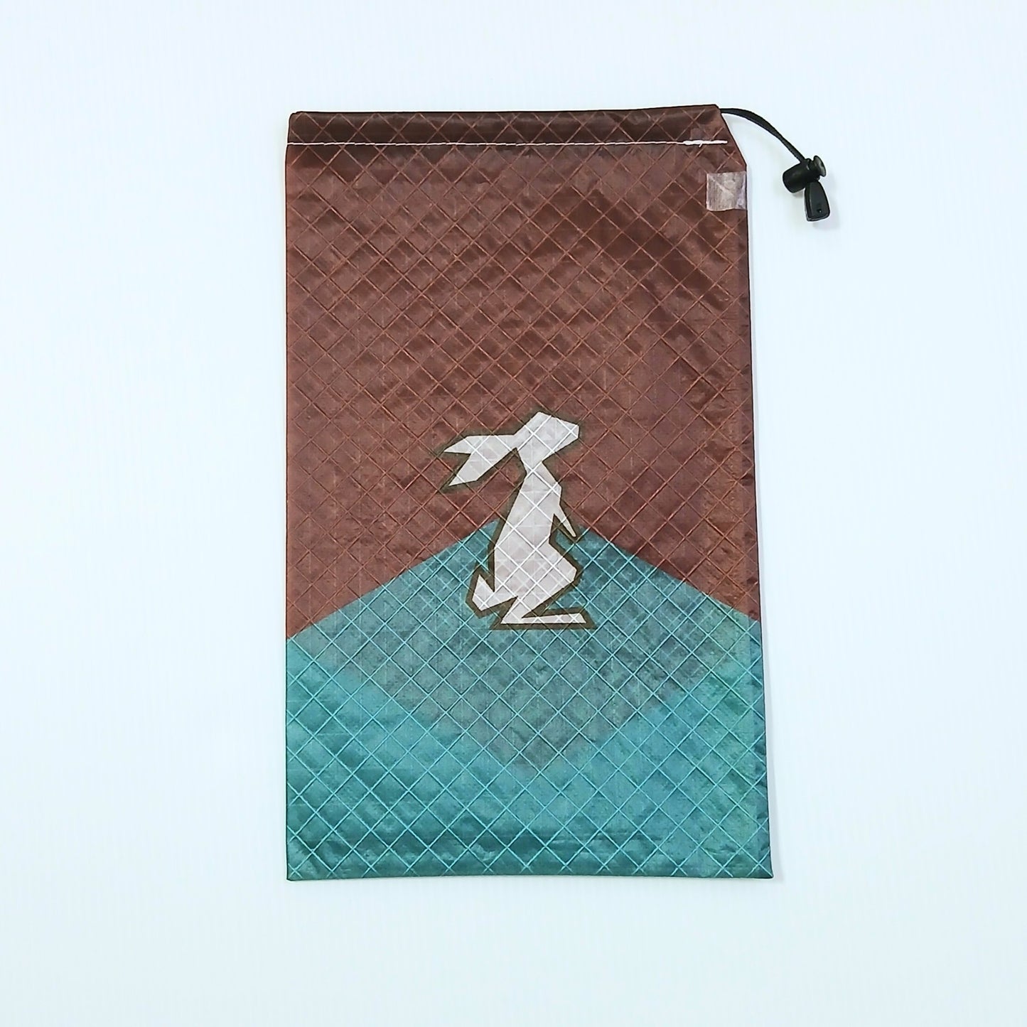 High Tail Designs Ultralight Drawstring Stuff Sack ドローストリングスタッフサック Rust Cadet 赤錆色の上半分とティールブルーの山を組み合わせたカラーブロック柄、稜線をまたぐ位置に白いウサギのシルエットの実物写真 - 山道具とULギアのお店 Ascend Lite