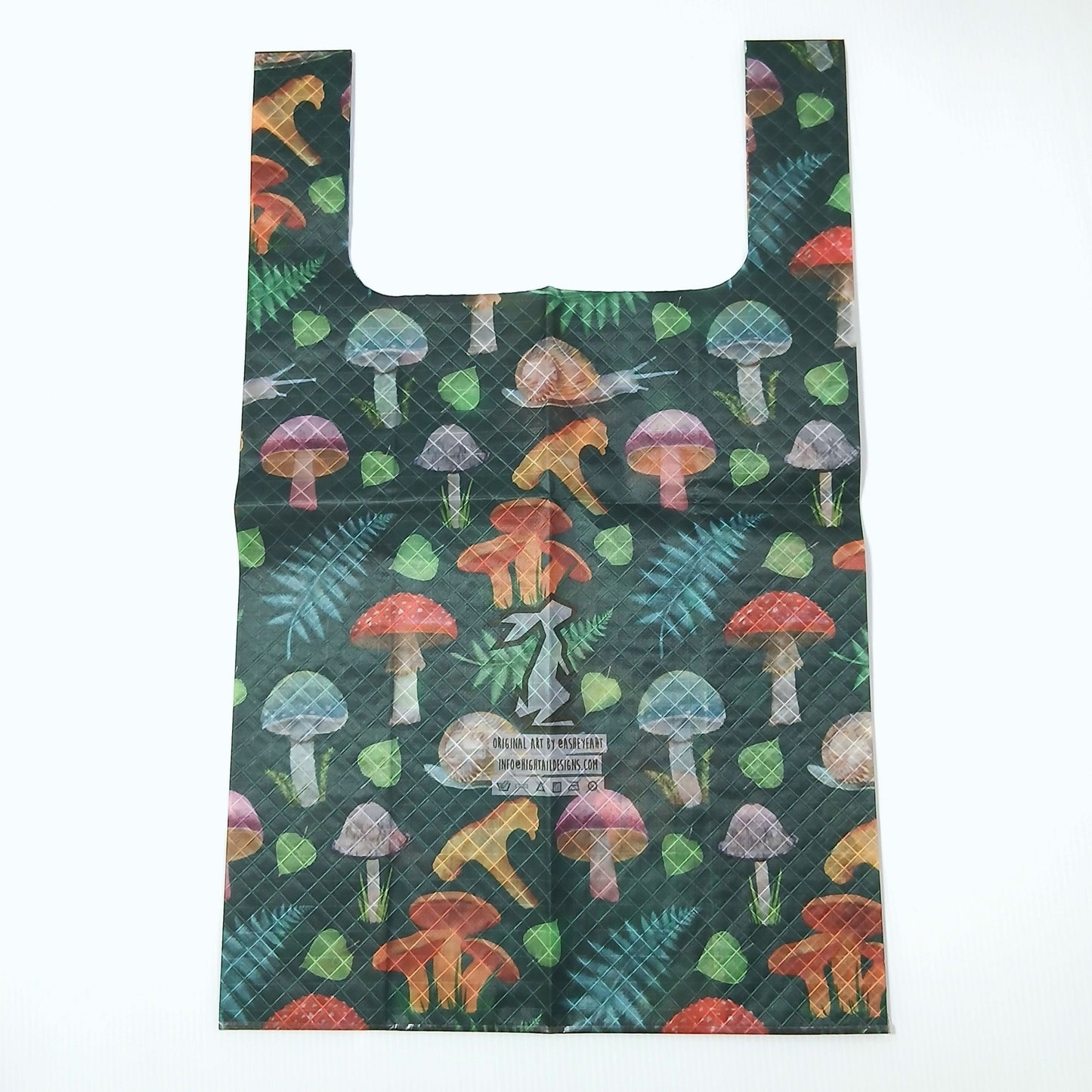 High Tail Designs TX Medium Shopping Bag ショッピングバッグ M Forest Mushroom（Ash Ryan） 深緑地に青緑のシダとハート型の葉、赤・紫・橙のキノコとカタツムリを描いた柄。幅広ハンドルの平置き正面全体と、中央のアーティストクレジット印字ケアタグの実物写真 - 山道具とULギアのお店 Ascend Lite