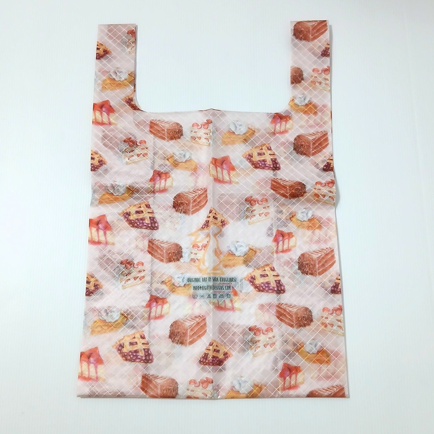 High Tail Designs TX Medium Shopping Bag ショッピングバッグ M Cakes & Pies（Sara Kruglinski） 半透明の淡いピンク地にチョコレートケーキやベリーパイ、ショートケーキの水彩イラストを散らした柄。折りジワの残る平置き正面全体と中央のケアタグの実物写真 - 山道具とULギアのお店 Ascend Lite