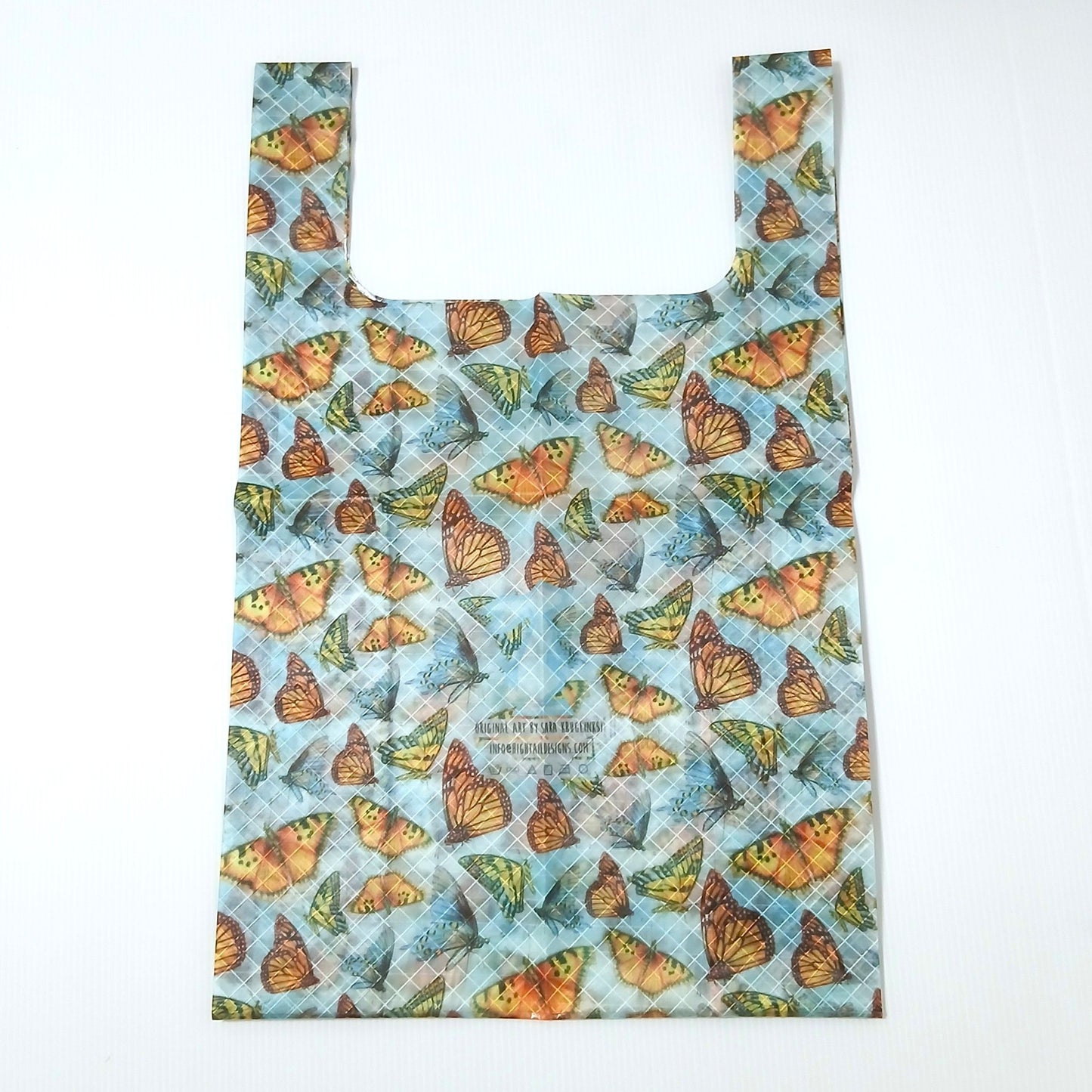 High Tail Designs TX Medium Shopping Bag ショッピングバッグ M Butterflies（Sara Kruglinski） 淡い水色地に橙・黄・茶の蝶を隙間なく敷き詰めた柄で、斜め45°のクロスプライ格子が透ける。平置き正面全体と中央のアーティストクレジット印字ケアタグの実物写真 - 山道具とULギアのお店 Ascend Lite