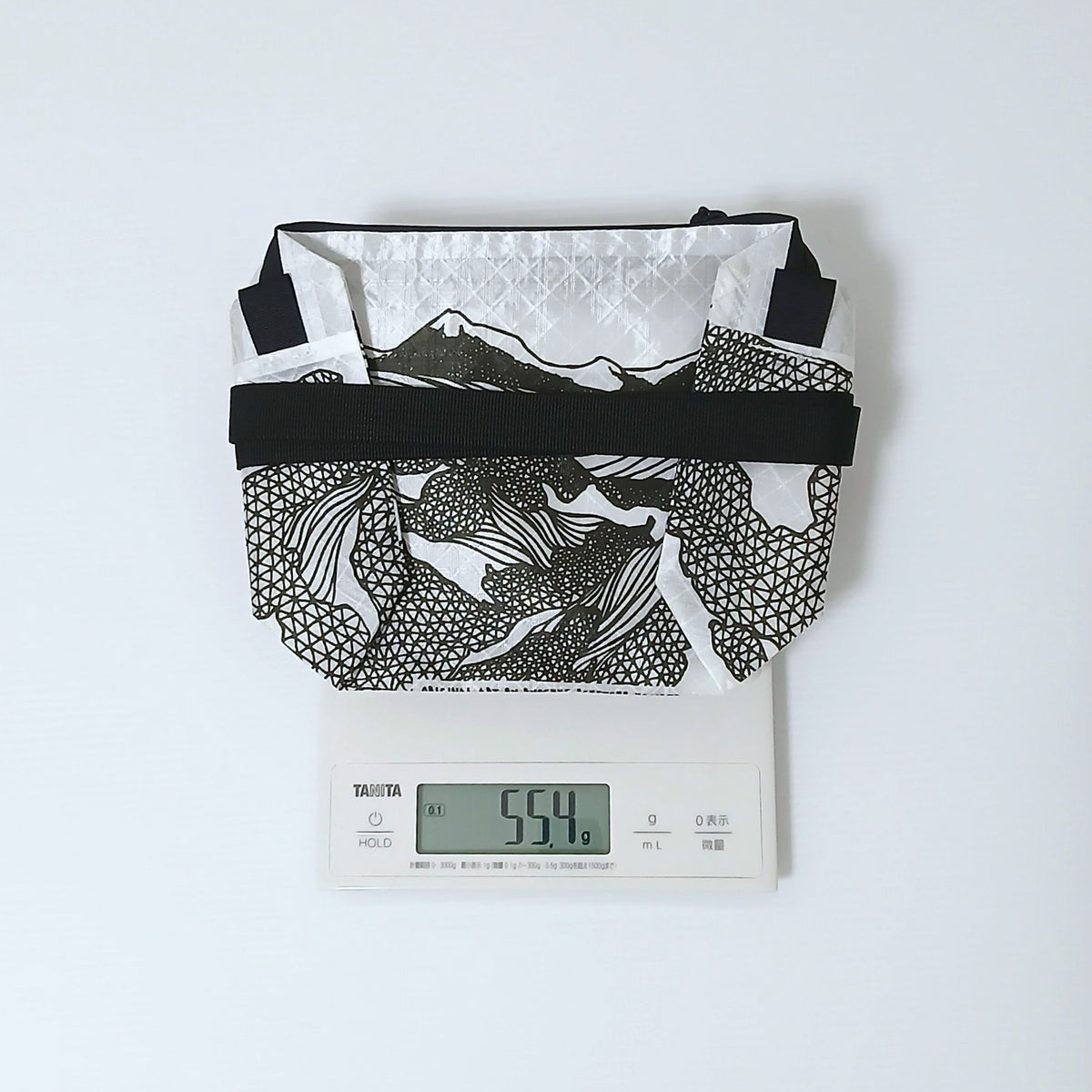 High Tail Designs The Ultralight Fanny Pack ファニーパック TX95 Low Poly 白地に黒の山並みと三角メッシュを描いた柄の本体をタニタのデジタルスケールに載せ、55.4gと表示された当店実測の重量写真 - 山道具とULギアのお店 Ascend Lite