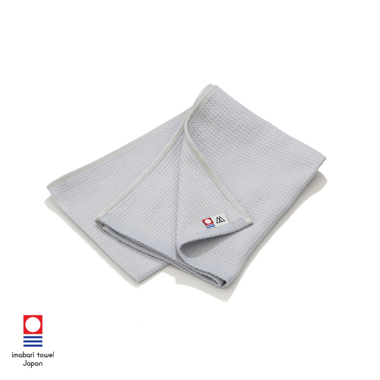 RIDGE MOUNTAIN GEAR Waffle Neck Wrap Towel ワッフルネックラップタオル Fog Blue を二つ折りにして角を折り返し今治タオル認定タグを見せた状態（公式画像） - 山道具とULギアのお店 Ascend Lite