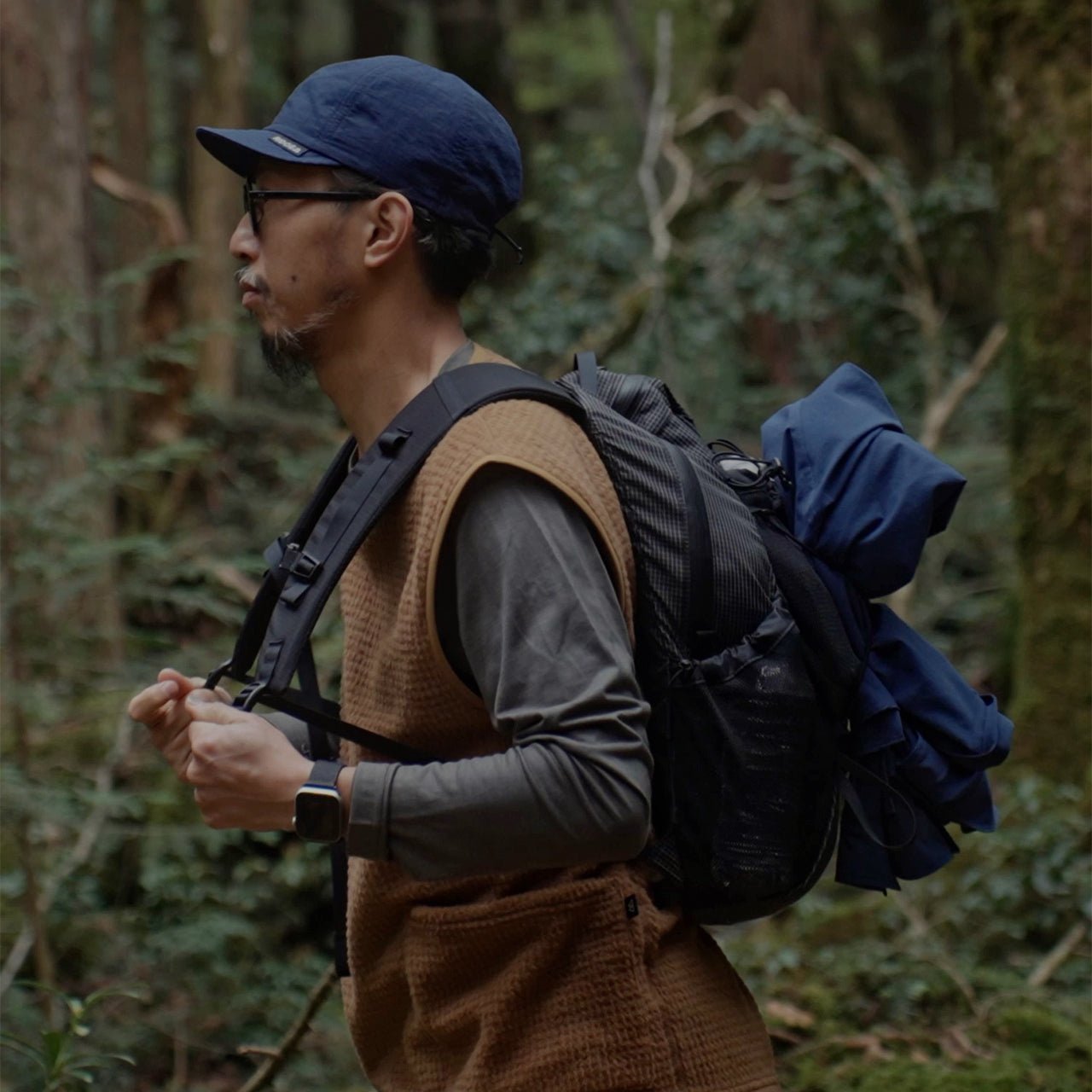 RIDGE MOUNTAIN GEAR One Mile MP ワンマイルMP サイドのコンプレッションコードにレインウェアを挟んで樹林帯を歩く使用シーン（公式画像） - 山道具とULギアのお店 Ascend Lite
