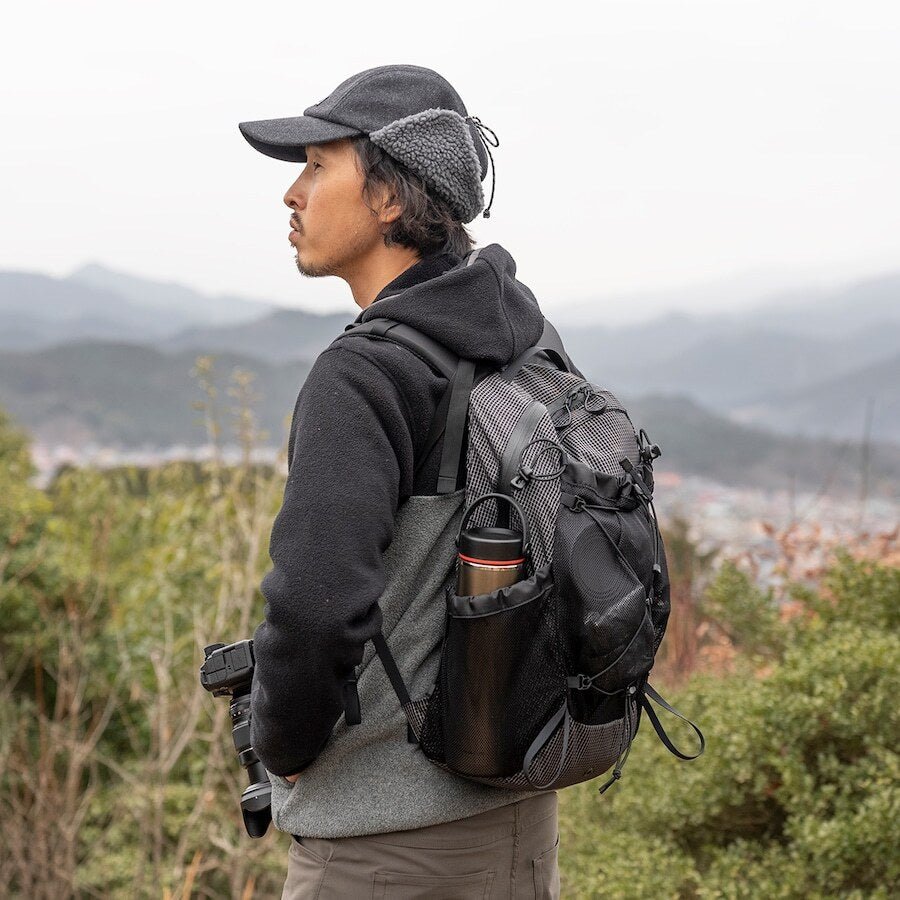 RIDGE MOUNTAIN GEAR One Mile MP ワンマイルMP 山を望む高台でサイドポケットに保温ボトルを収納して背負う使用シーン（公式画像） - 山道具とULギアのお店 Ascend Lite