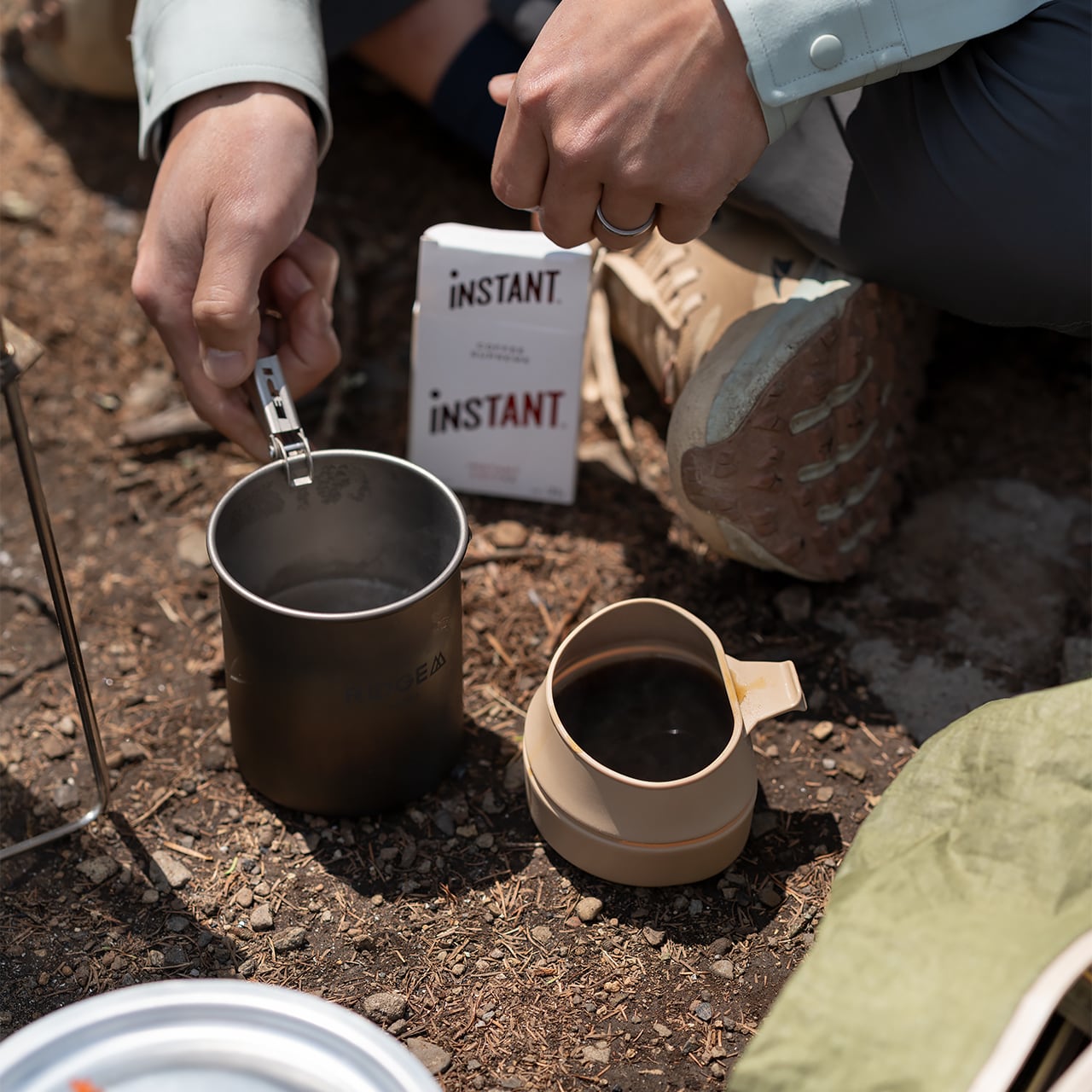 RIDGE MOUNTAIN GEAR Titanium Mug 450ml チタンマグ450ml 地面に置いた本体をリフターで持ち上げるコーヒー準備の様子（公式画像） - 山道具とULギアのお店 Ascend Lite