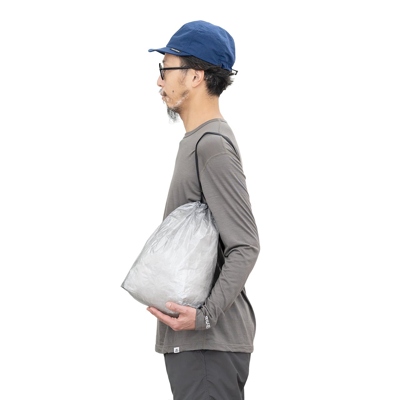 RIDGE MOUNTAIN GEAR Stuff Sack スタッフサック Nickel Grey を肩に掛けてサコッシュのように提げた着用例（公式画像） - 山道具とULギアのお店 Ascend Lite