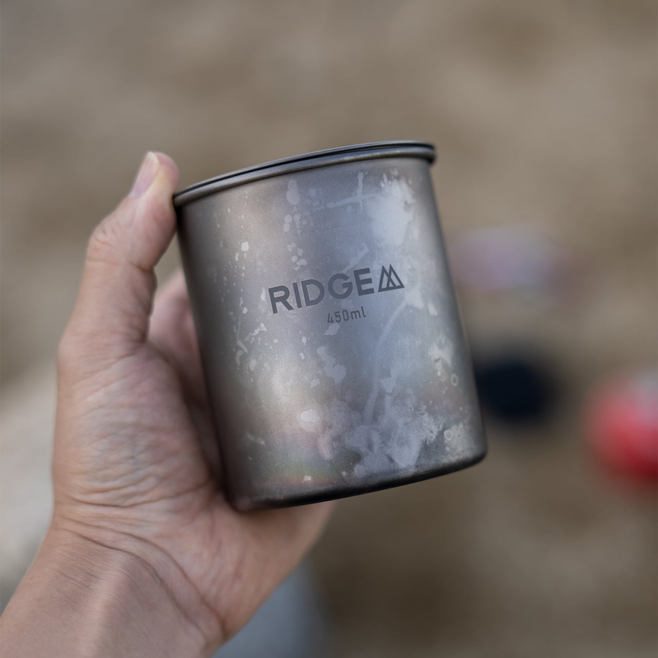 RIDGE MOUNTAIN GEAR Titanium Mug 450ml チタンマグ450ml 屋外で手に持った焼け色のついた使用後の外観（公式画像） - 山道具とULギアのお店 Ascend Lite