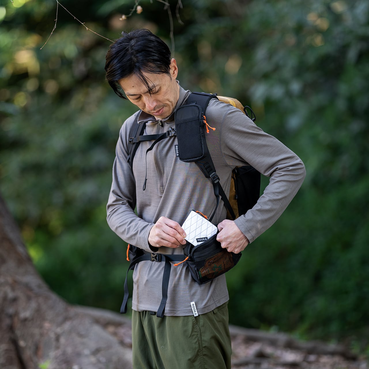 RIDGE MOUNTAIN GEAR Side Increase サイドインクリース ショルダーハーネスとウエストベルトに2個同時装着して小物入れを取り出す様子（公式画像） - 山道具とULギアのお店 Ascend Lite