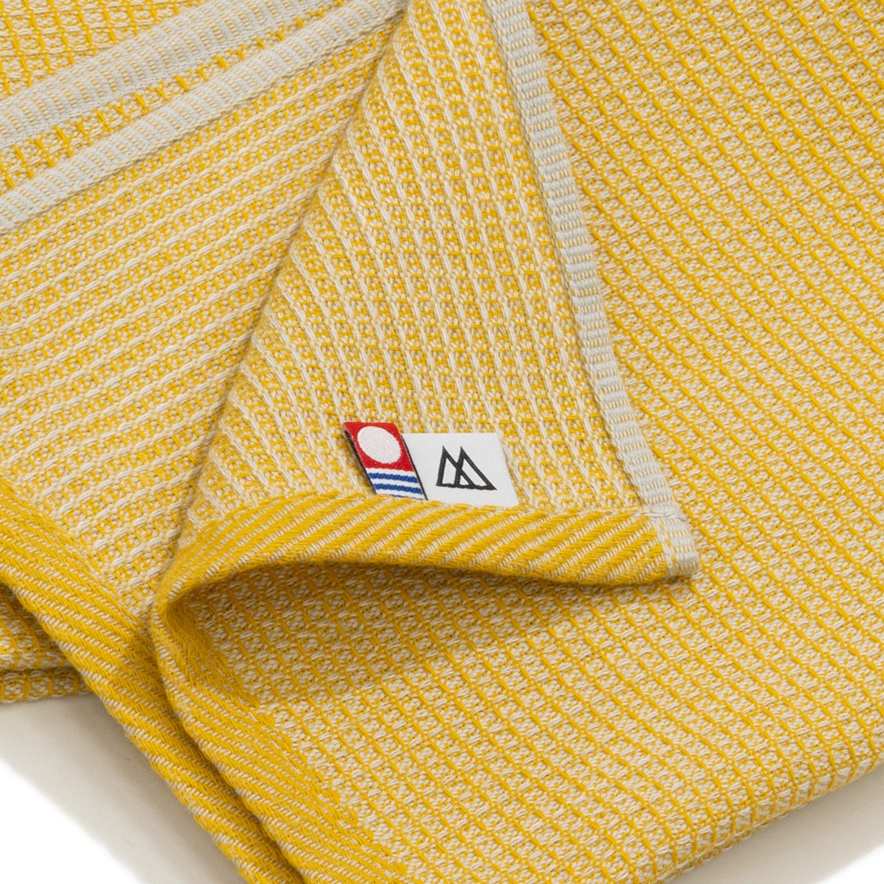 RIDGE MOUNTAIN GEAR Waffle Neck Wrap Towel ワッフルネックラップタオル Dry Wheat の端の縫製と今治タオル認定マークのタグを写したクローズアップ（公式画像） - 山道具とULギアのお店 Ascend Lite