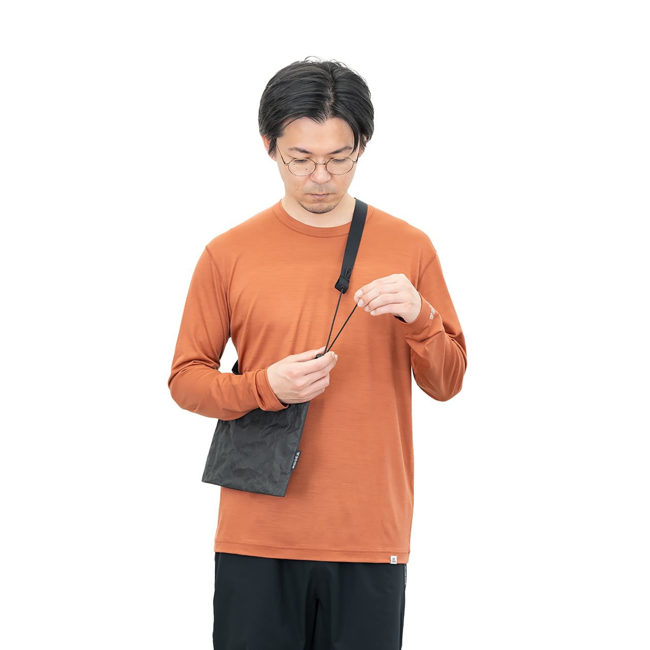 RIDGE MOUNTAIN GEAR Sacoche サコッシュ 着用例 コードを引いて肩掛けの長さを調整する様子（公式画像） - 山道具とULギアのお店 Ascend Lite