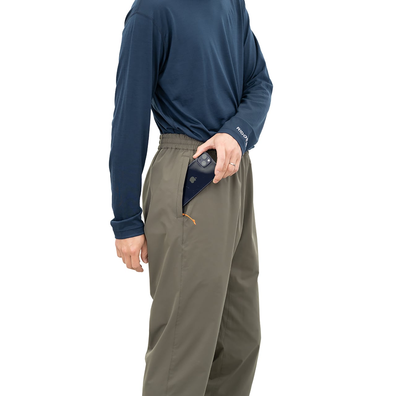 RIDGE MOUNTAIN GEAR Unwind Pants アンワインドパンツ Faded Taupe 着用時に左脇のファスナーポケットへスマートフォンを出し入れする様子とオレンジのジッパープル（公式画像） - 山道具とULギアのお店 Ascend Lite
