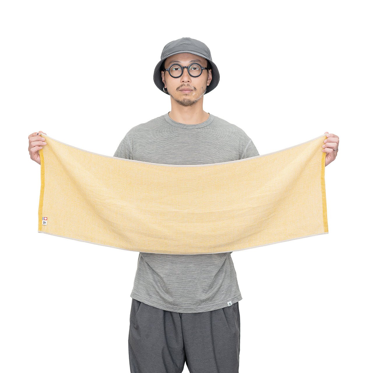 RIDGE MOUNTAIN GEAR Waffle Neck Wrap Towel ワッフルネックラップタオル Dry Wheat を男性が両手で左右に広げて全長約102cmを示した着用例（公式画像） - 山道具とULギアのお店 Ascend Lite