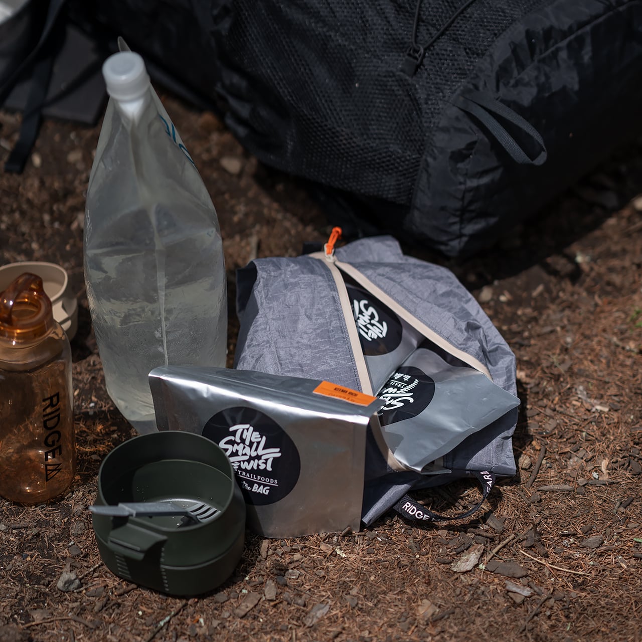 RIDGE MOUNTAIN GEAR JUN OSON×RIDGE Case M ケースM ファスナーを全開にしてアルミパウチの行動食を収納した屋外での使用シーン（無地モデル・公式画像） - 山道具とULギアのお店 Ascend Lite