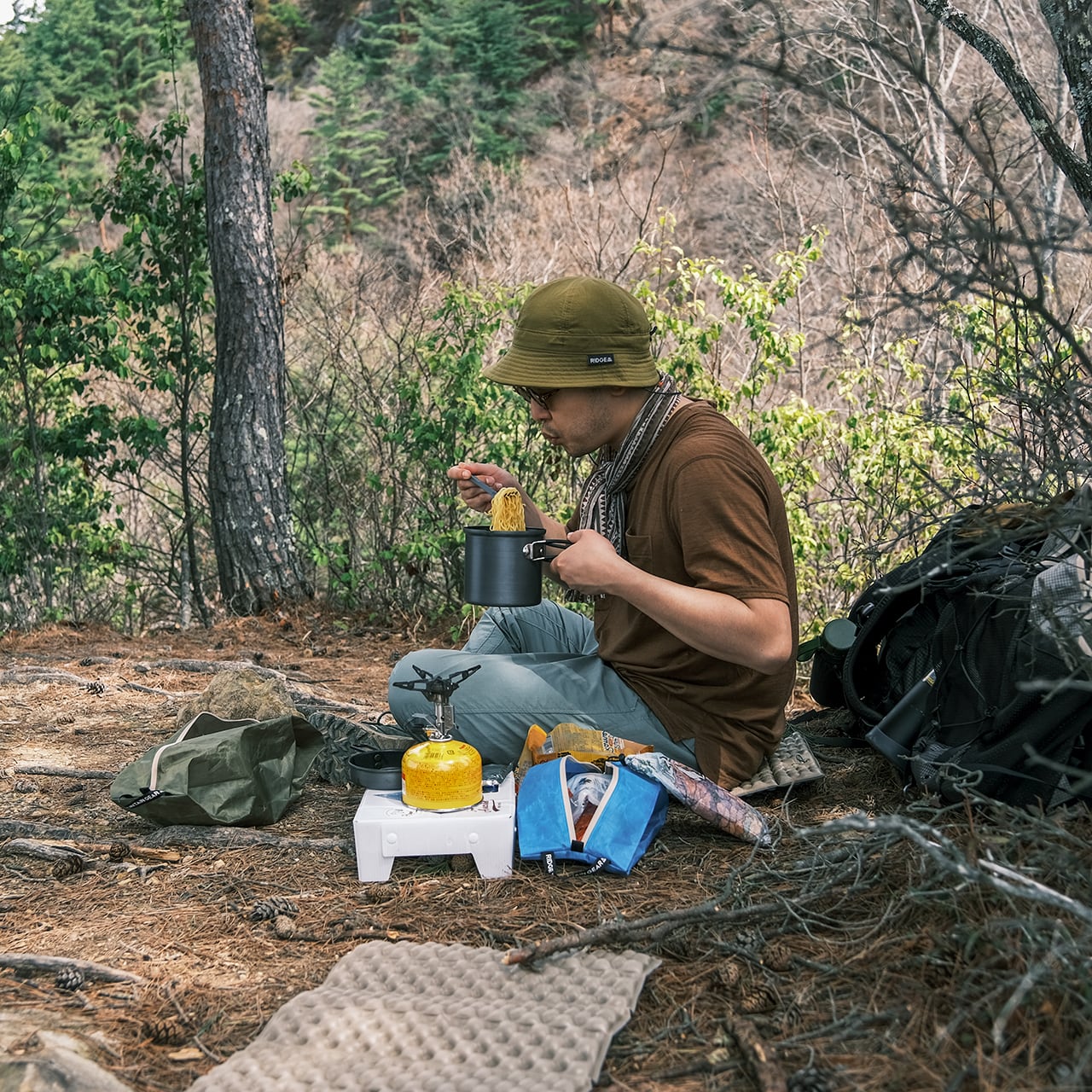RIDGE MOUNTAIN GEAR Case L ケースL Cyan Blue に行動食を入れて山中の休憩地に広げた使用シーン（公式画像） - 山道具とULギアのお店 Ascend Lite