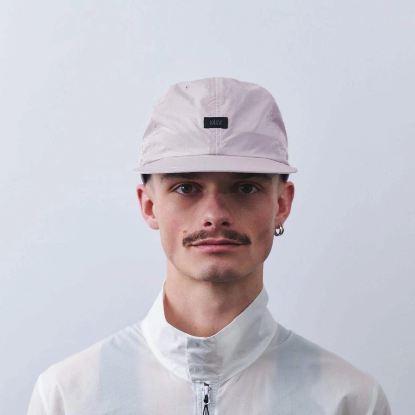 VAGA Drift Cap ドリフトキャップ ダスティライラック 着用イメージ 正面（公式画像） - 白いジャケット姿の男性、浅めの被り位置とフロントの黒いVAGAラベルの見え方 - 山道具とULギアのお店 Ascend Lite
