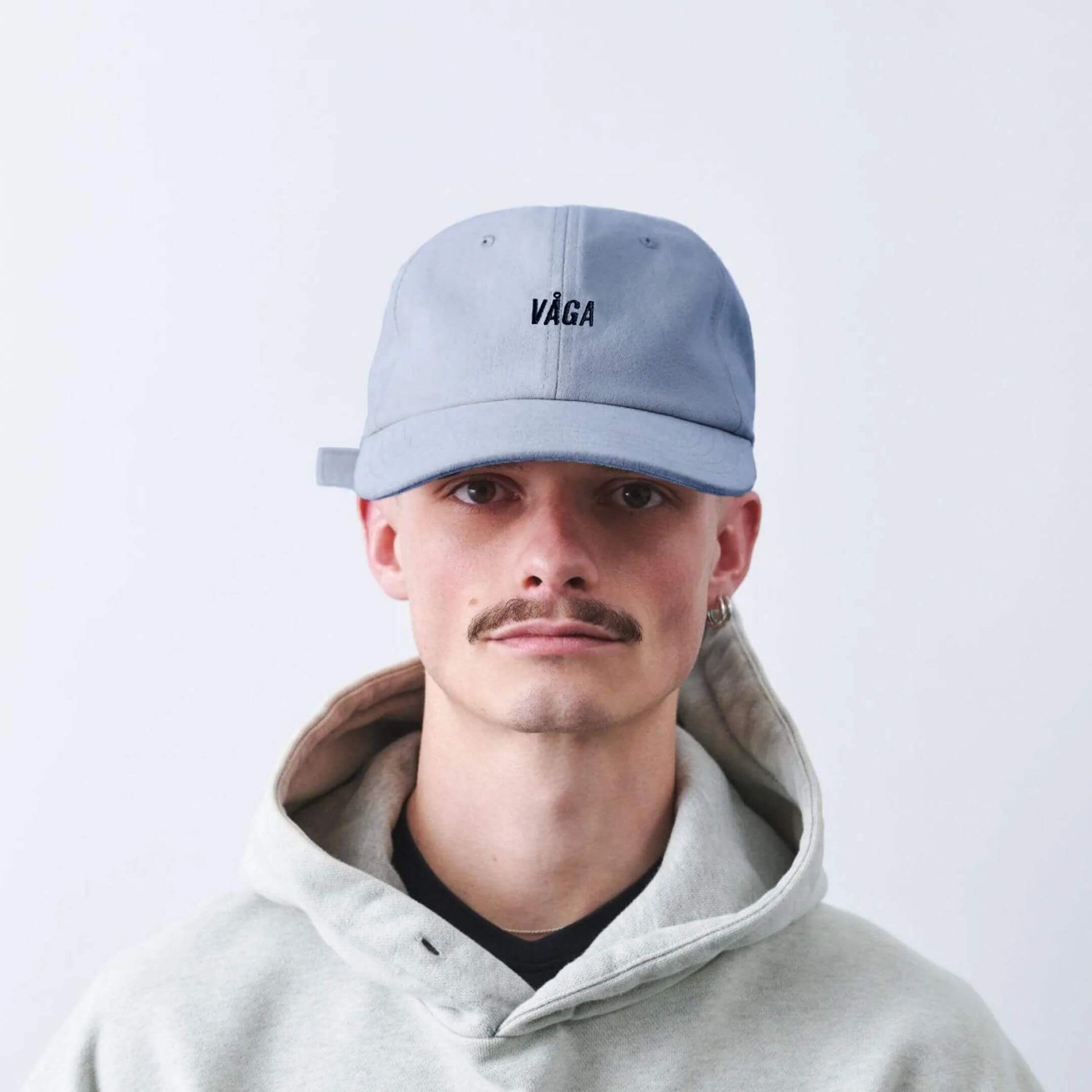 VAGA Washed Cotton Cap ウォッシュドコットンキャップ ポスタルブルー 着用イメージ 正面（公式画像） - フーディー姿の男性が浅めに被った状態、つばの丸みとロゴの見え方 - 山道具とULギアのお店 Ascend Lite