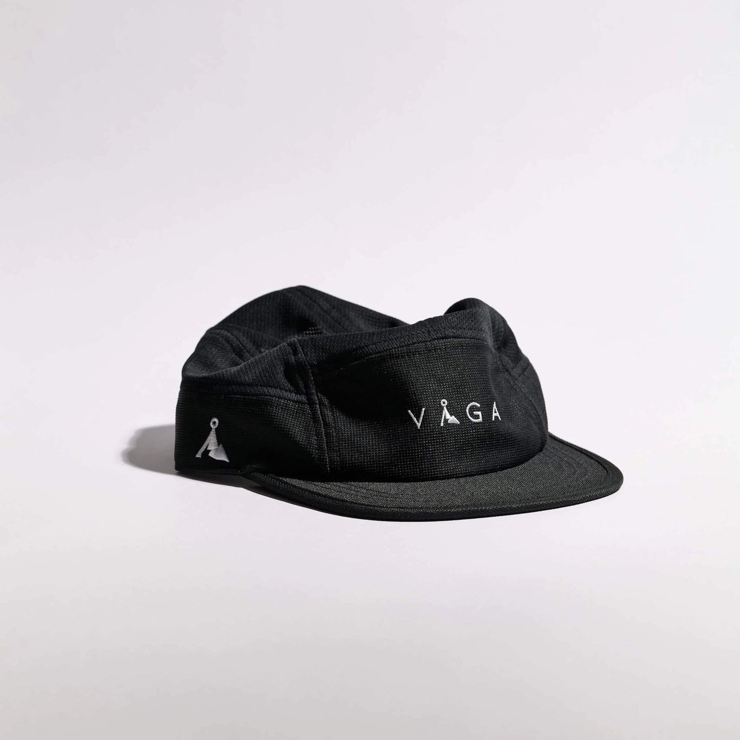 VAGA Club Cap クラブキャップ ストームブラック 斜め前（公式画像） - フロント中央の白いVAGAロゴとサイドの山型ロゴ、格子目の入った黒生地と短いつば - 山道具とULギアのお店 Ascend Lite