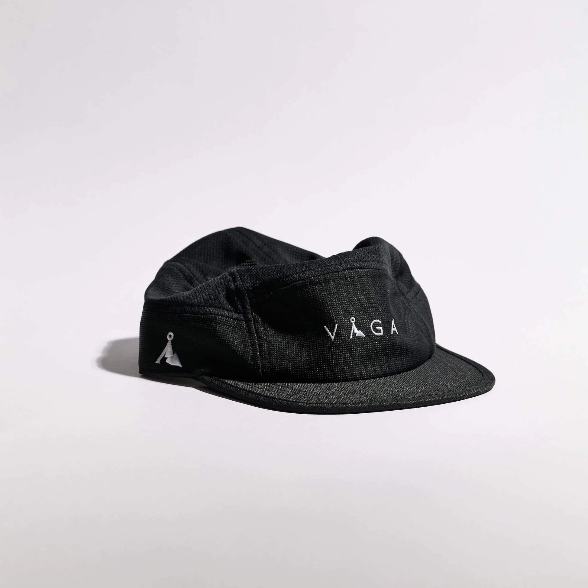 VAGA Club Cap クラブキャップ ストームブラック 斜め前（公式画像） - フロント中央の白いVAGAロゴとサイドの山型ロゴ、格子目の入った黒生地と短いつば - 山道具とULギアのお店 Ascend Lite