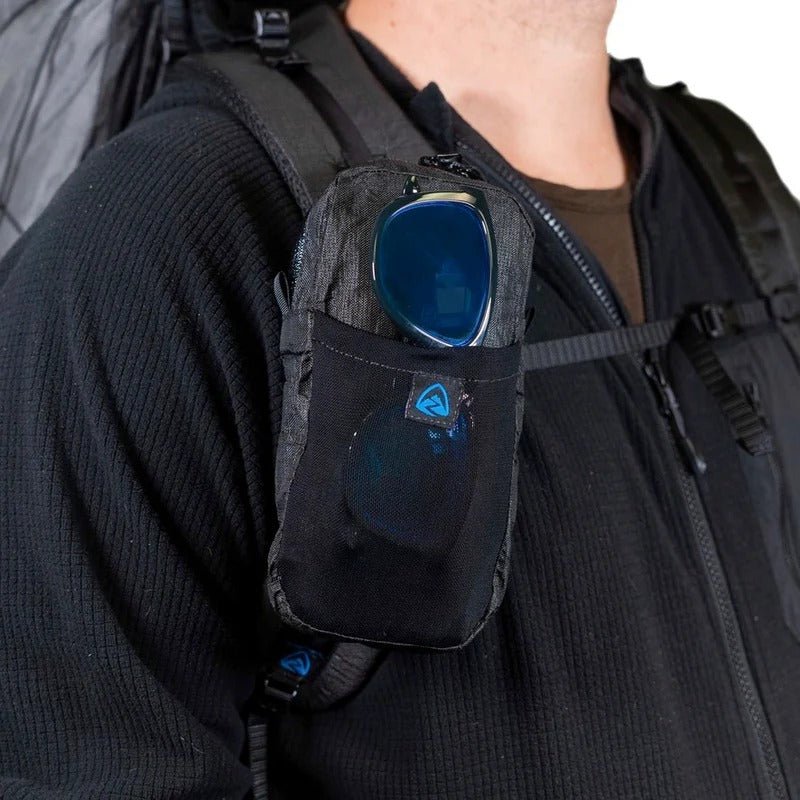 Zpacks Shoulder Pouch w/ Zipper ショルダーポーチ ジッパー付き Jet Black Ultra 着用例を斜め前から、フロント伸縮メッシュポケットにサングラスを差した状態とショルダーストラップに沿った縦長の収まり（公式画像） - 山道具とULギアのお店 Ascend Lite
